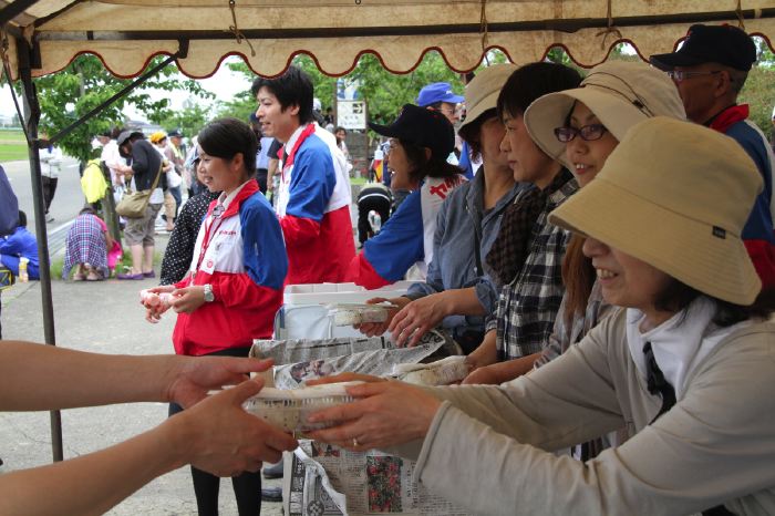 田んぼアートの田植え、参加者に昨年の田んぼアートで収穫しtアコメのおにぎり