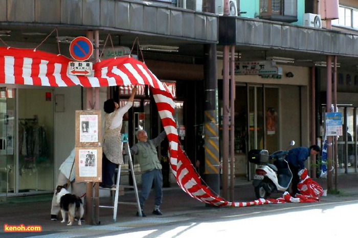 15日に大名行列が進む大通りに紅白幕を下げて準備する商店